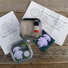 Small sheep plush toy in packaging with a label on a wooden surface