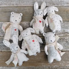 Set of small stuffed animals with embroidered faces on a wooden surface