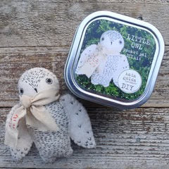 Embroidered toy bear with a tin labeled 'Little Bear' on a wooden surface