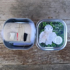 Small tin with embroidered fabric and a decorative lid on a wooden surface