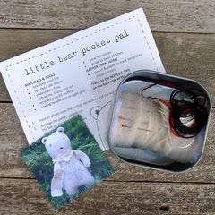 Small bear pocket pal with packaging and instructions on a wooden surface