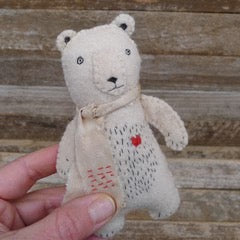 Handmade teddy bear with a red heart on a wooden background