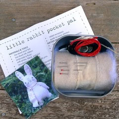 Small metal tin with rabbit-themed items on a wooden surface