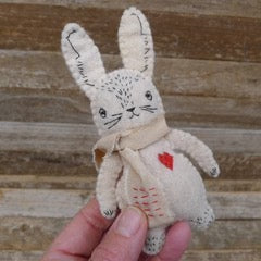 Handmade rabbit plush toy with a heart on a wooden surface