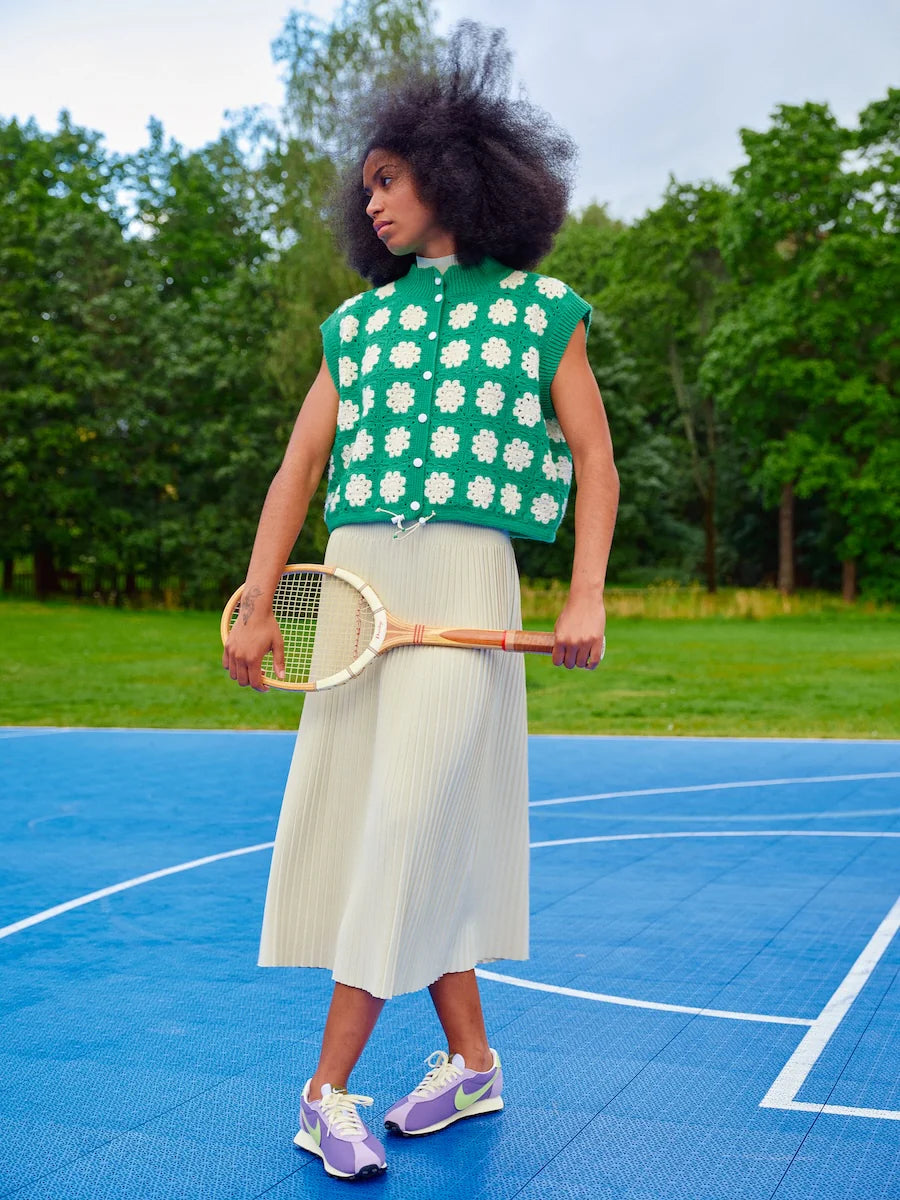 Woman holding a tennis racket on a blue court with green trees in the background