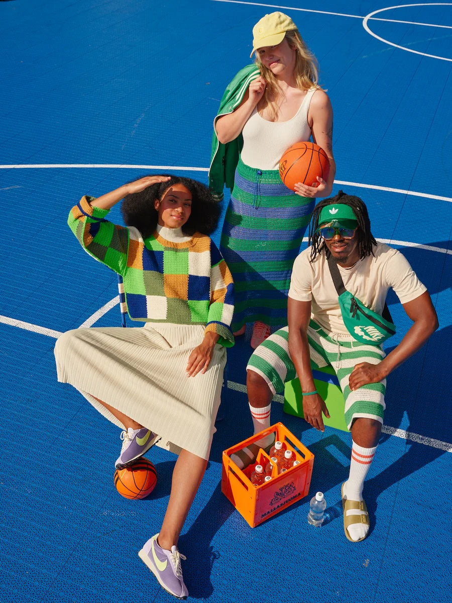 Three people posing on a basketball court with sports-themed clothing and accessories.