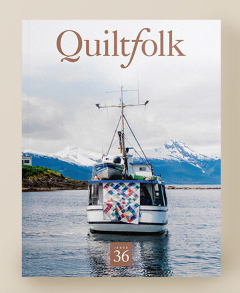an Alaskan boat on water with a colorful quilt on the bow