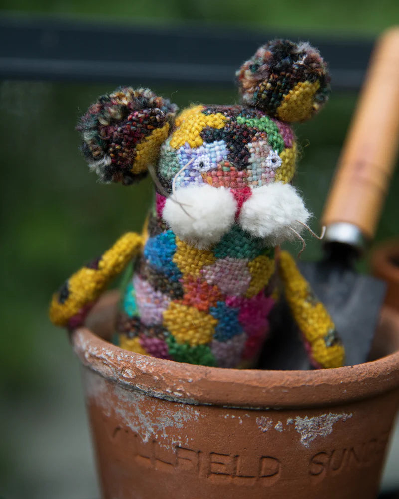 a colorful embroidered animal in a clay pot