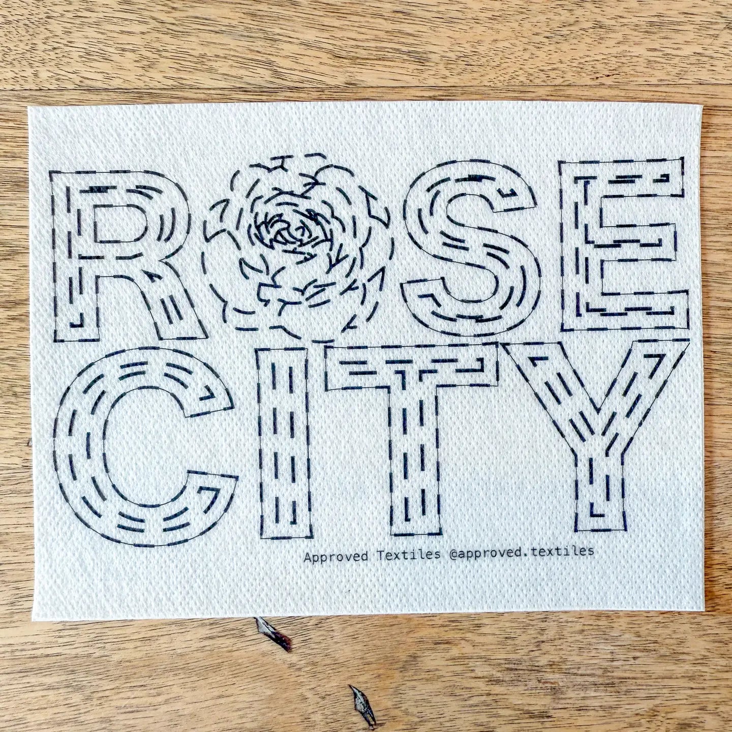 Textile with 'Rose City' design on a wooden surface