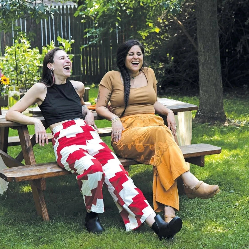 2 people sitting on a bench wearing quilted pants