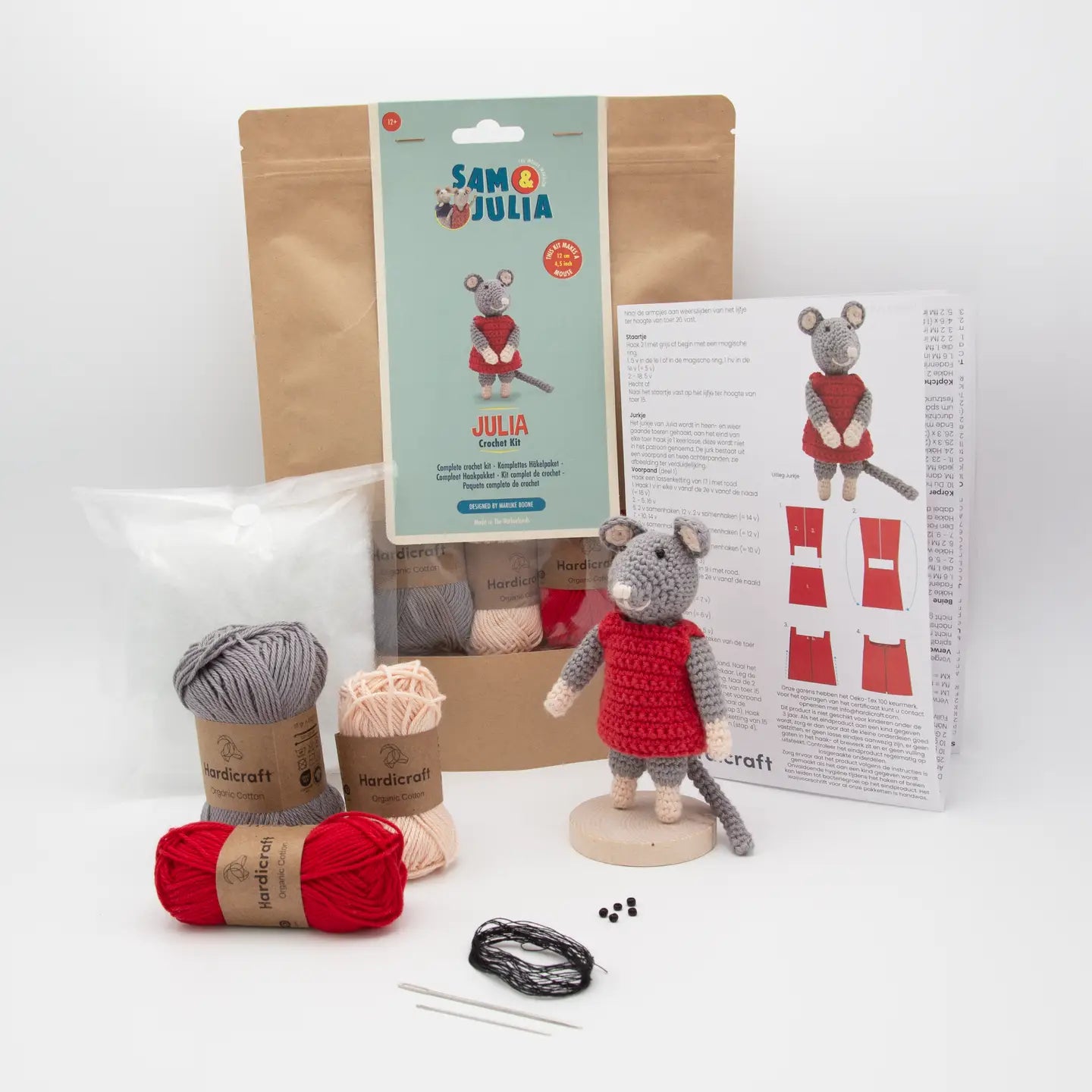 Craft kit with yarn, a small crocheted mouse toy, packaging, and instructions on a white background.