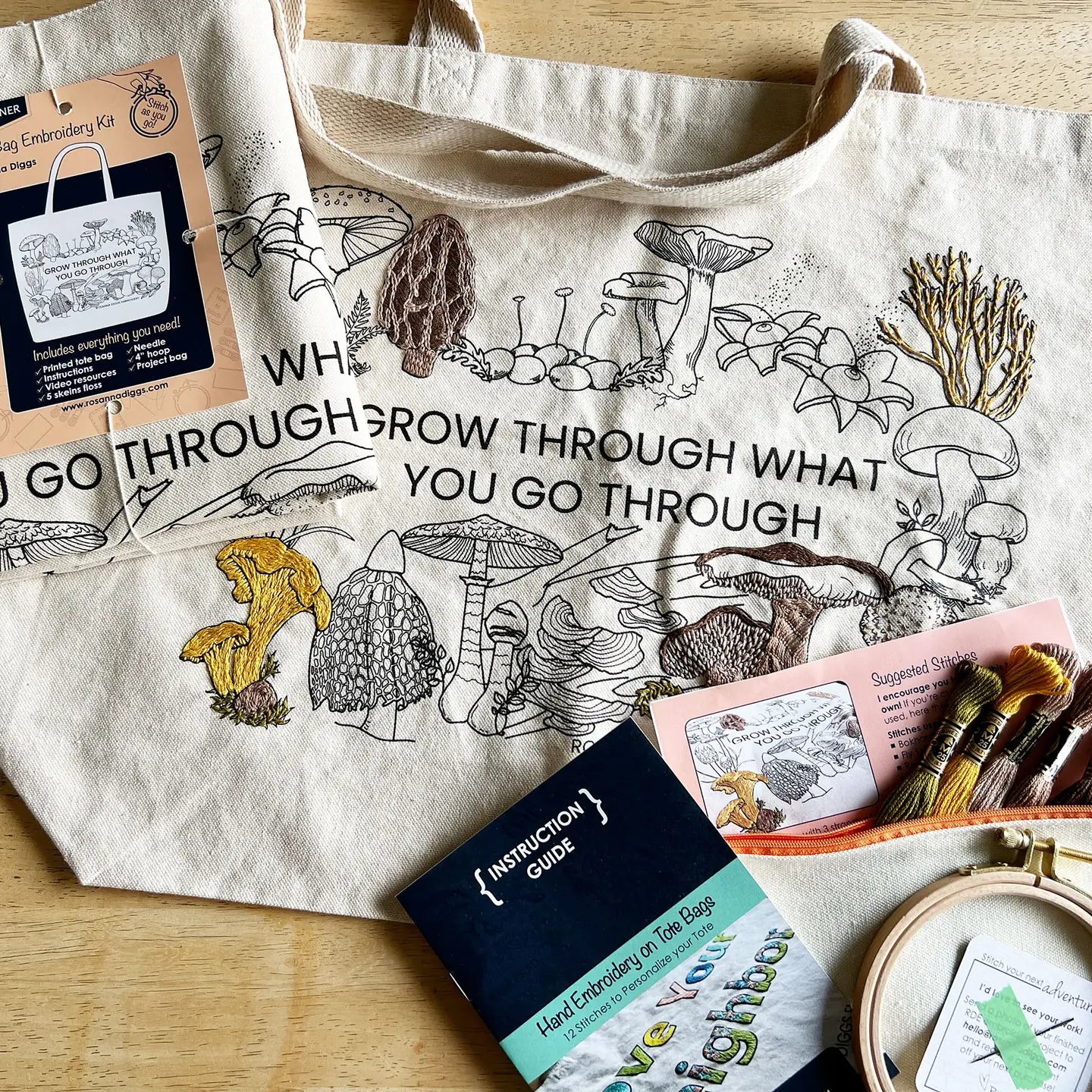 Embroidery kit with tote bag featuring mushroom design and motivational quote on a wooden surface.