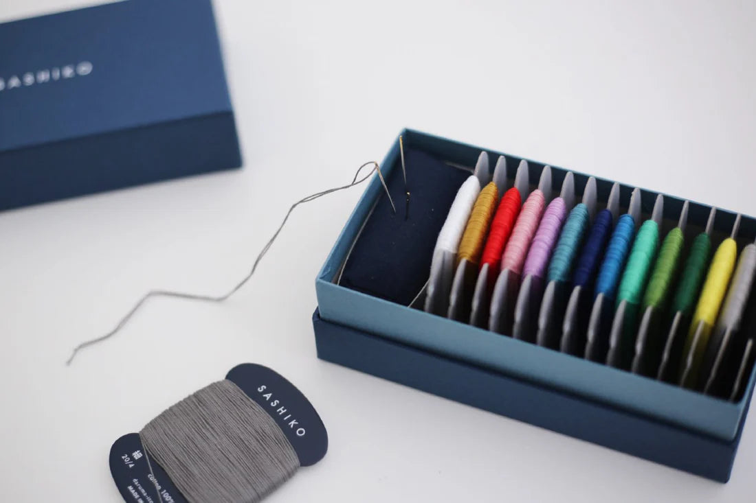 a blue box with sashiko thread, needles and a pincushion