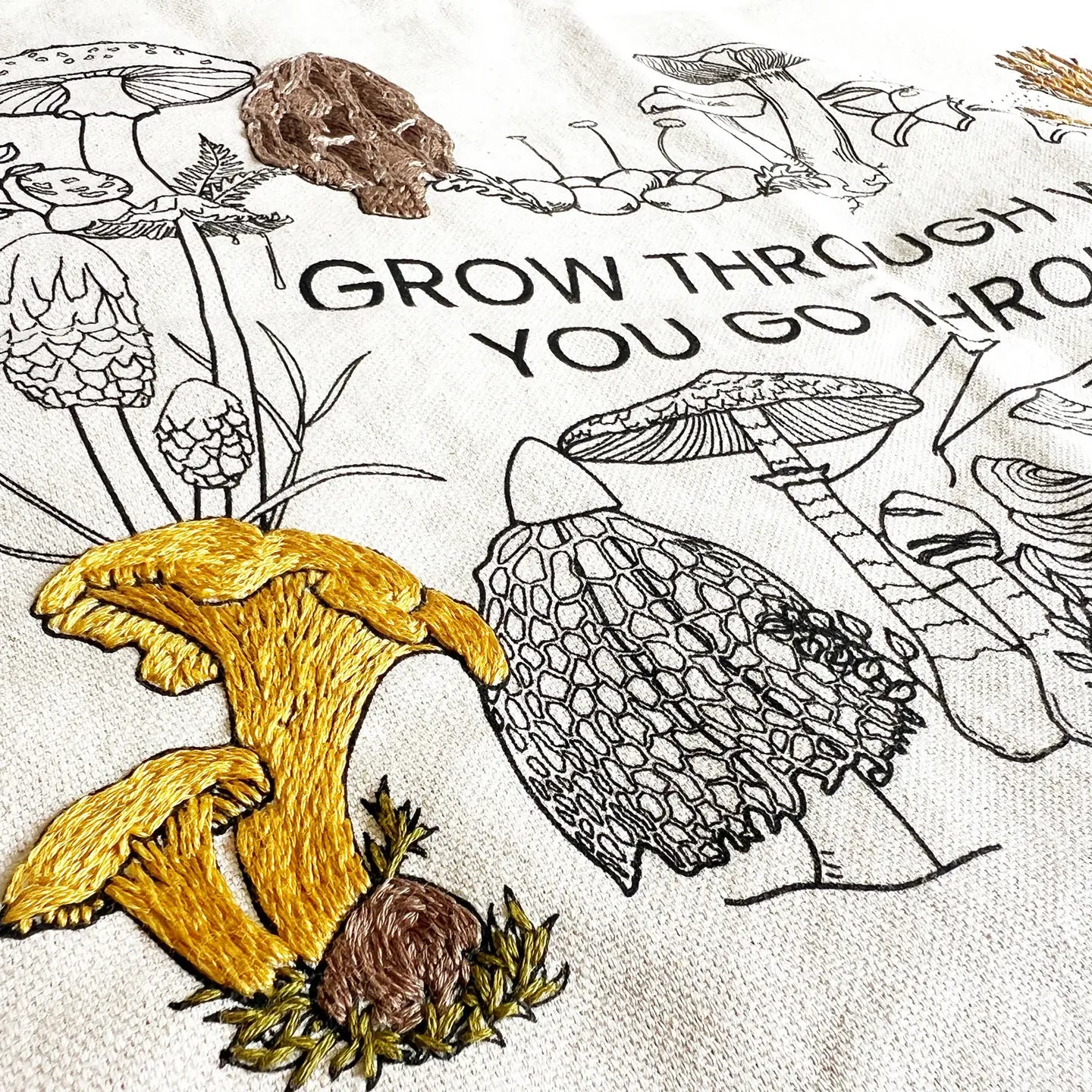 mushroom illustrations and text 'GROW THROUGH YOU GO THROUGH', on a textured fabric background.