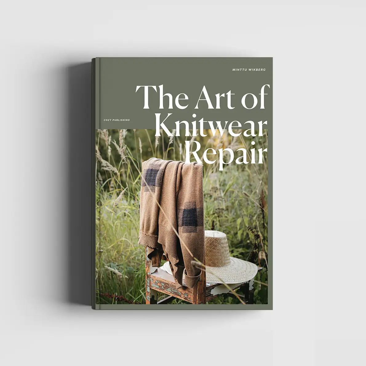 Book titled 'The Art of Knitwear Repair' with a cover featuring a brown sweater on a chair in a natural setting.