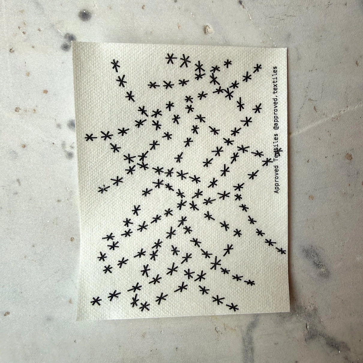 Textile sample with black star pattern on a textured beige background