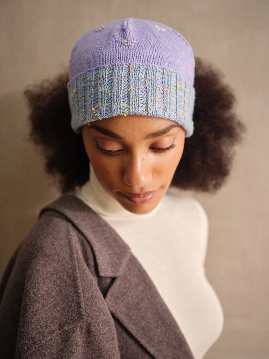 Person wearing a knitted hat with a gradient design against a neutral background