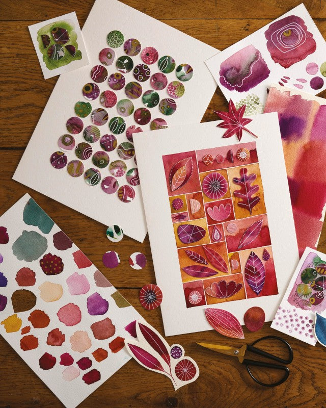 Colorful art prints and stickers on a wooden surface with scissors.