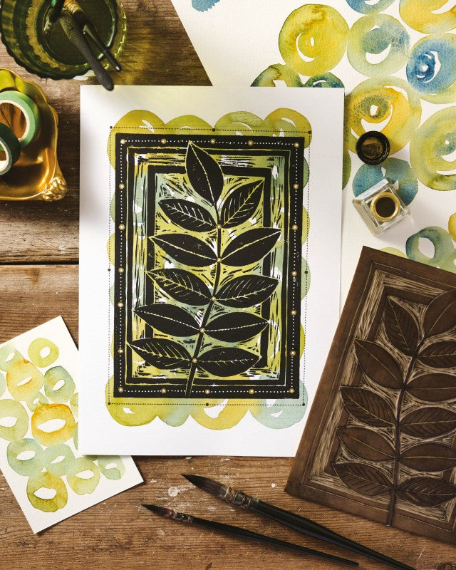 Artistic print of leaves with a wooden stamp and ink bottle on a wooden surface