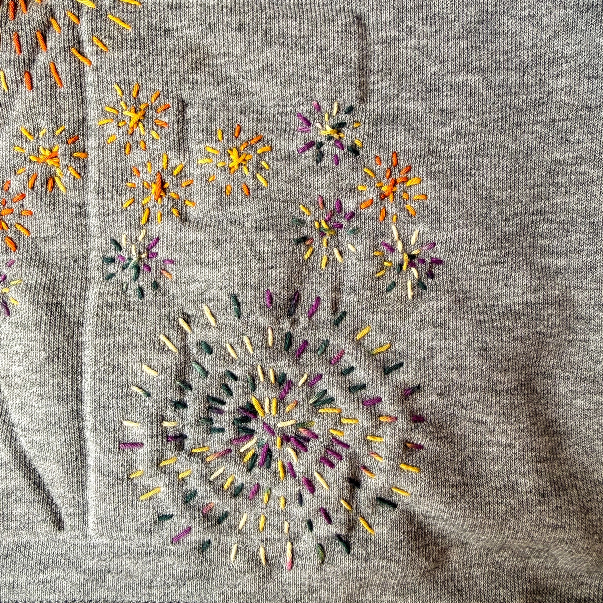 Embroidered floral pattern on a gray fabric background