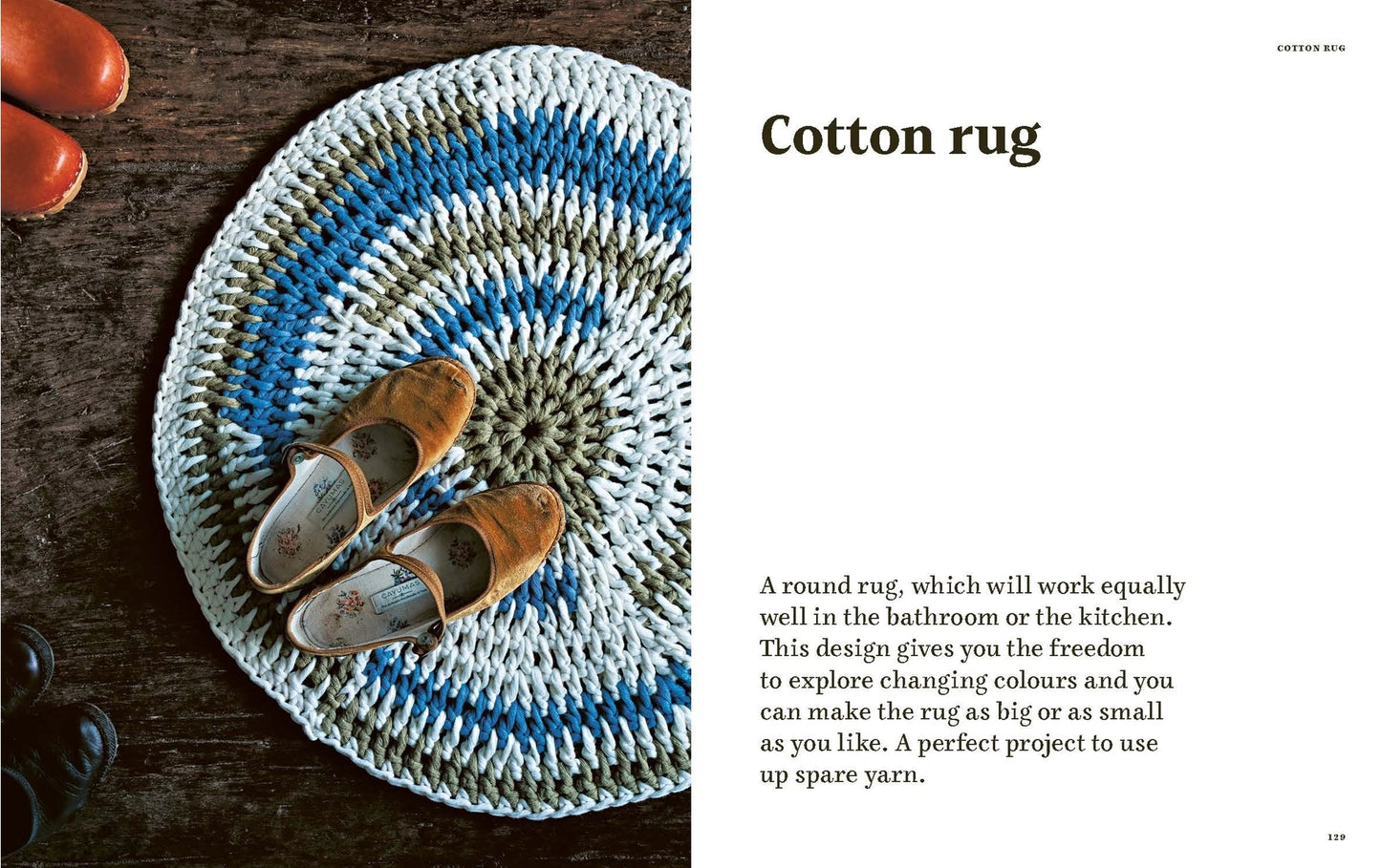 A circular crocheted cotton rug with concentric rings of blue, white, and gray, styled on a dark wooden surface with a pair of brown slip-on shoes. 