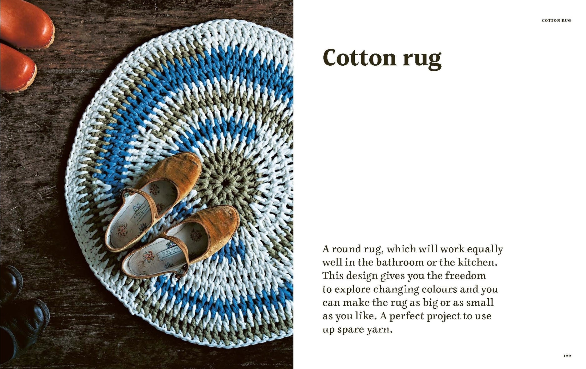 A circular crocheted cotton rug with concentric rings of blue, white, and gray, styled on a dark wooden surface with a pair of brown slip-on shoes. 