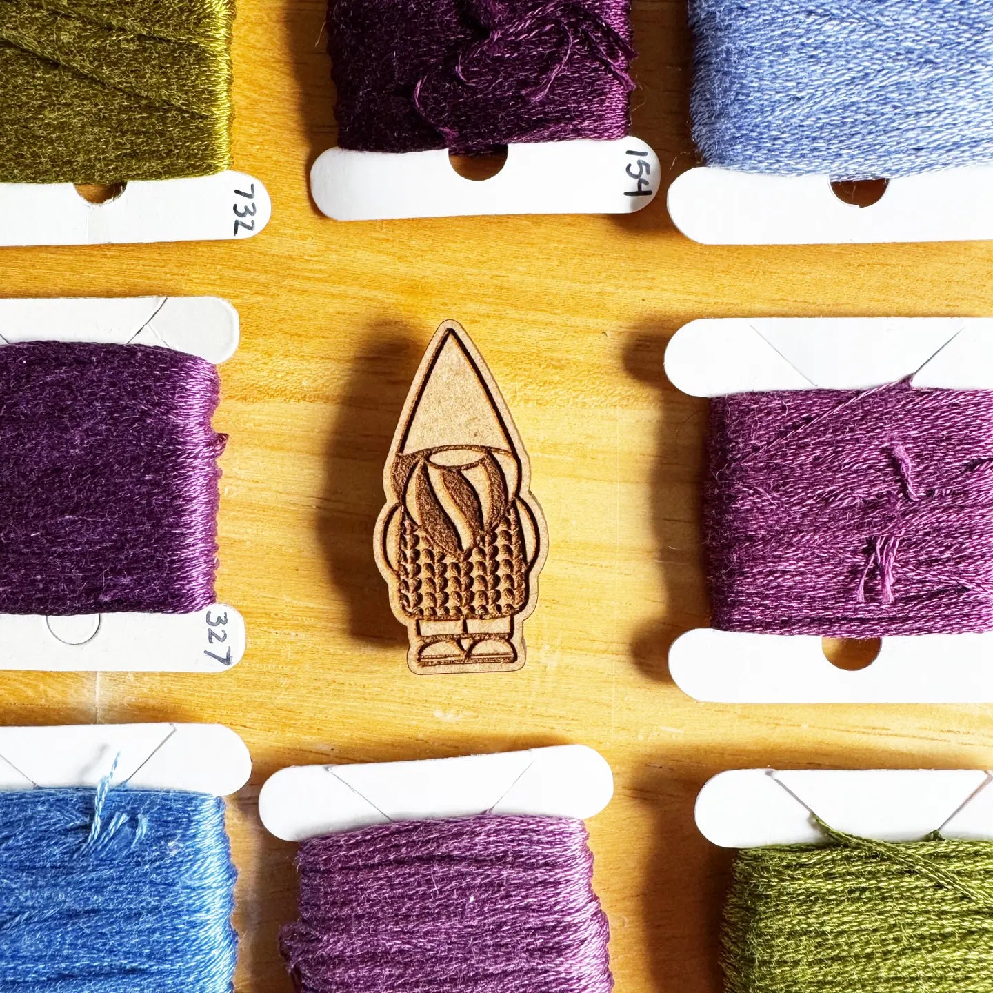 Wooden needle minder with colorful yarn spools 