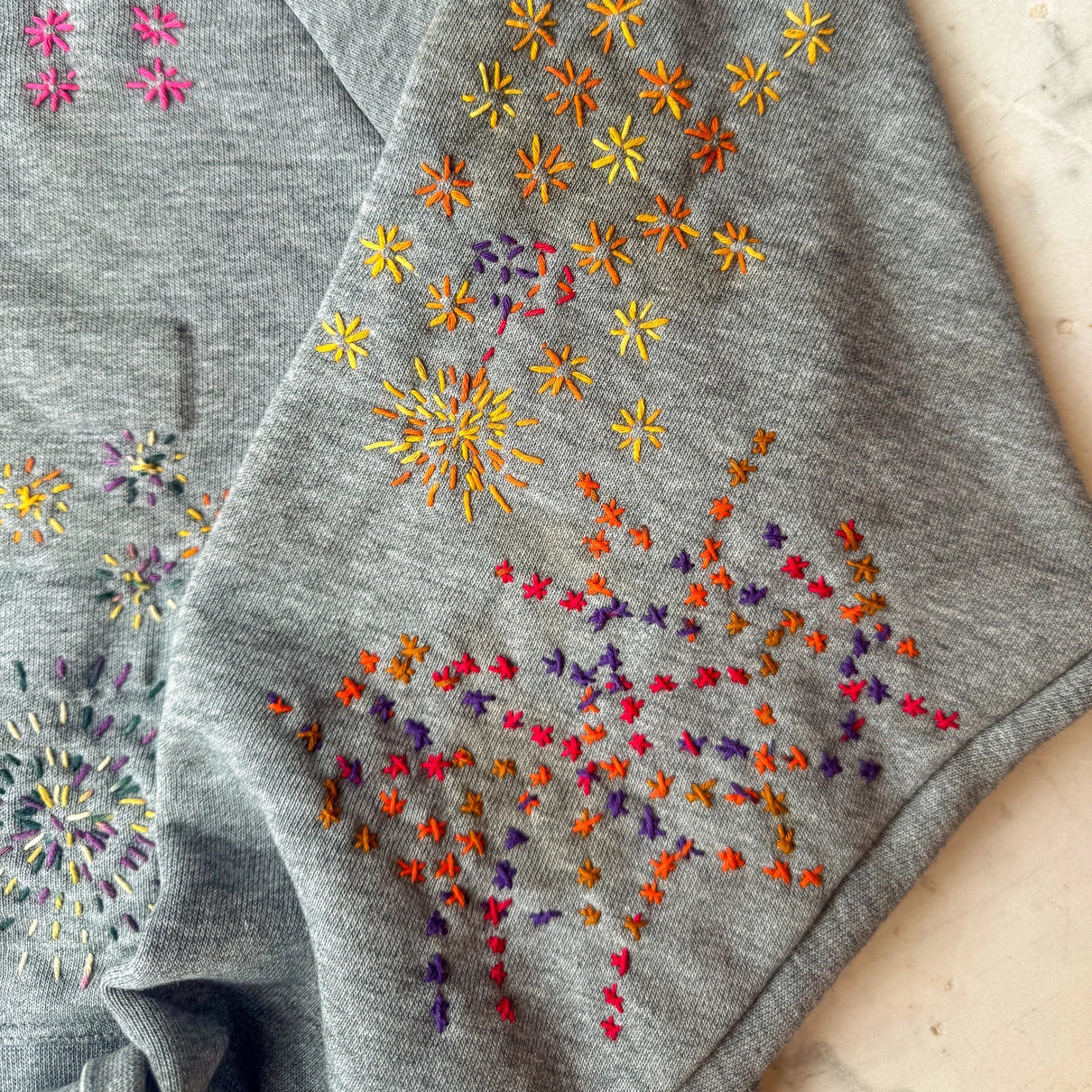 Gray fabric with colorful embroidered floral patterns on a wooden surface